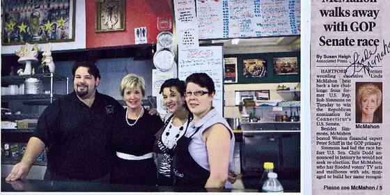 The family behind the counter with Linda McMahon, beside a signed newspaper clipping
