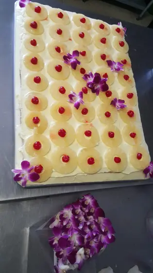 A Hawaiian pineapple cake decorated with purple edible flowers